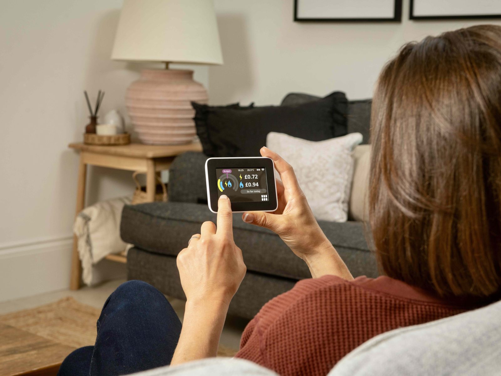 Woman holding smart meter in-home display showing energy costs